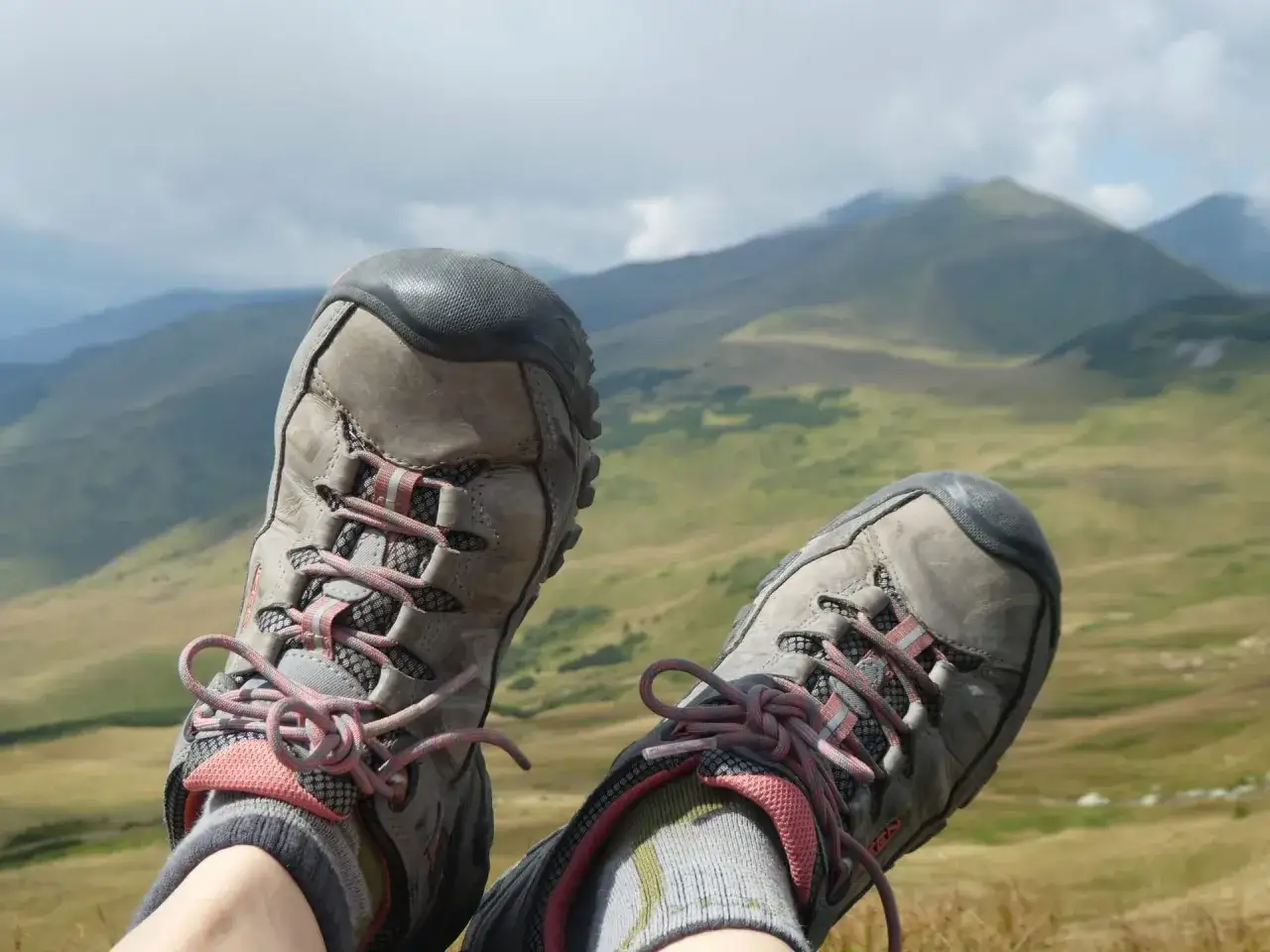 Wygodne buty w góry to podstawa udanej wędrówki. Te szare trekkingowe buty z różowymi sznurówkami i skarpetkami zapewniają komfort na szlaku.
